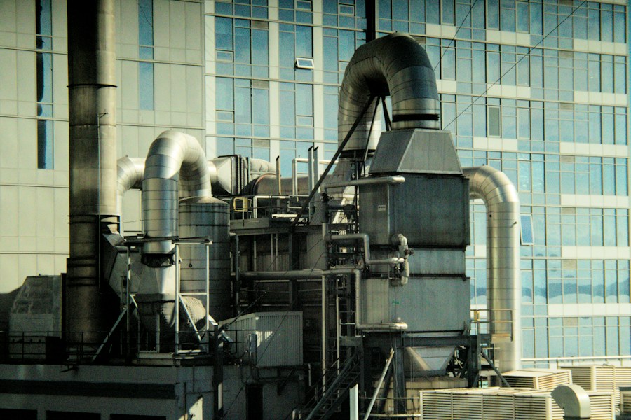 Industrial machinery with large pipes against a modern glass building